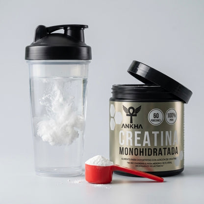Shaker con creatina monohidratada Ankha disolviéndose en agua junto a cuchara medidora y pote 100% puro, 60 porciones
